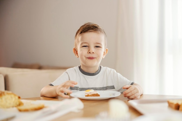 Ritratto di un ragazzino felice che mangia colazione a casa