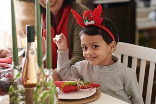 Ritratto di un ragazzino sorridente a cena di natale con la famiglia