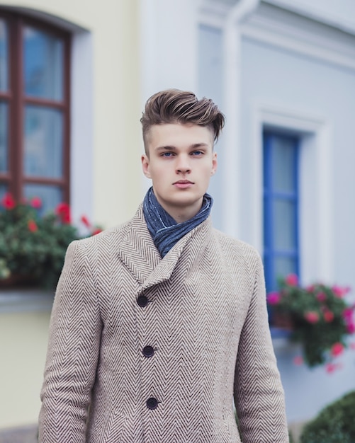 Ritratto di un ragazzo alla moda in un cappotto e sciarpa. moda autunnale