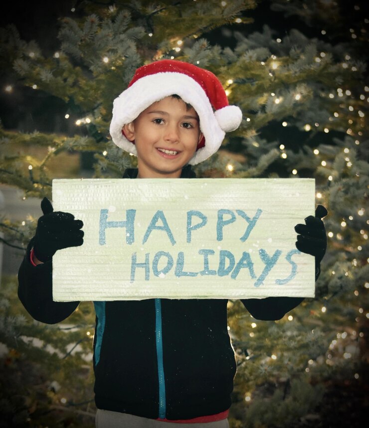 Foto ritratto di un ragazzo che tiene un testo su carta contro l'albero di natale