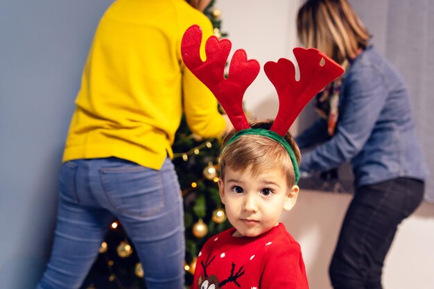 Ritratto di un ragazzo con i genitori che decorano l'albero di Natale a casa