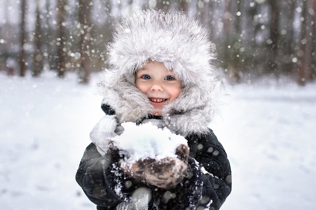 Ritratto di un ragazzo con un cappello invernale di pelliccia. Inverno, all'aperto, neve.