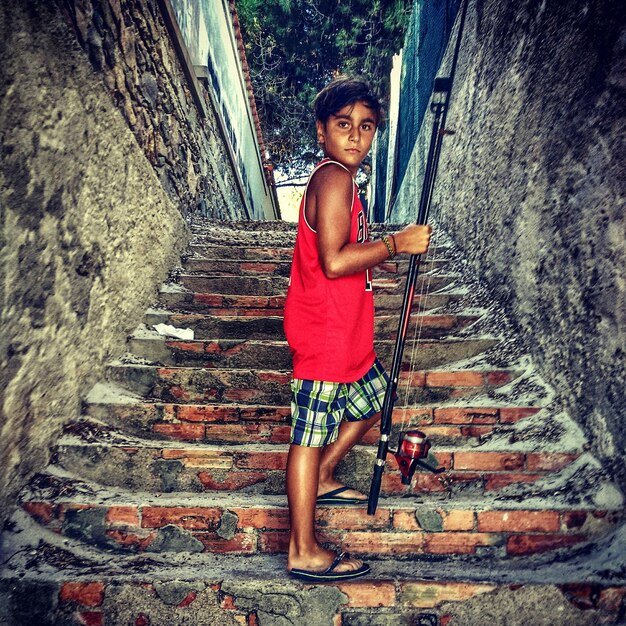 Ritratto di un ragazzo con una canna da pesca in piedi sui gradini