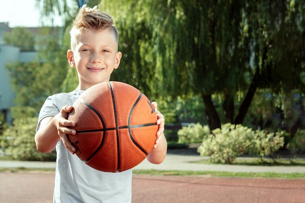 Ritratto di un ragazzo con una pallacanestro su un campo da pallacanestro