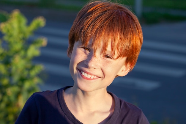 Ritratto di un ragazzo dai capelli rossi carino sorridente sulla strada dietro un passaggio pedonale