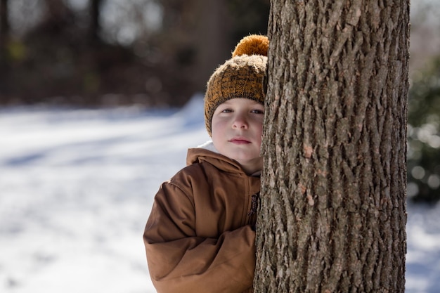 Ritratto di un ragazzo di cinque anni in piedi nella neve fresca in inverno che gioca all'aperto