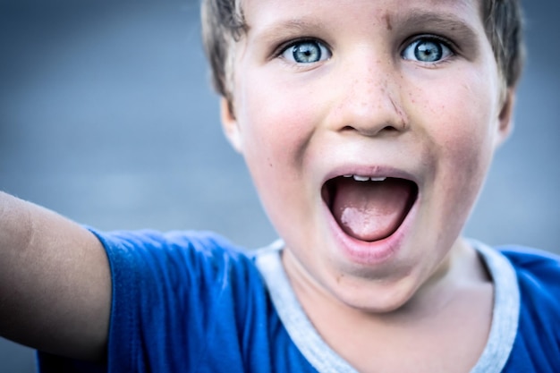 Ritratto di un ragazzo divertente felice malizioso allegro biondo dagli occhi azzurri che fa le lentiggini faccia sporca mentre gioca ridendo Concetto di relazione familiare di educazione dell'infanzia felice dell'asilo nido