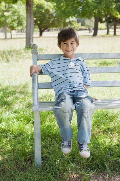 Ritratto di un ragazzo felice seduto sulla panchina al parco