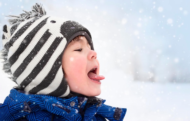 ritratto di un ragazzo in inverno che cattura i fiocchi di neve con la lingua