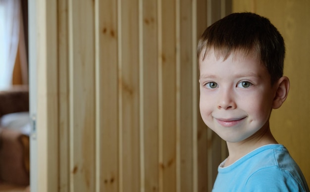 Ritratto di un ragazzo sorridente, su uno sfondo di legno, copia dello spazio. Ragazzo carino di aspetto europeo, con una fossetta sulle guance