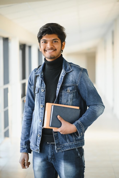 Ritratto di un ragazzo universitario indiano che tiene in mano dei libri