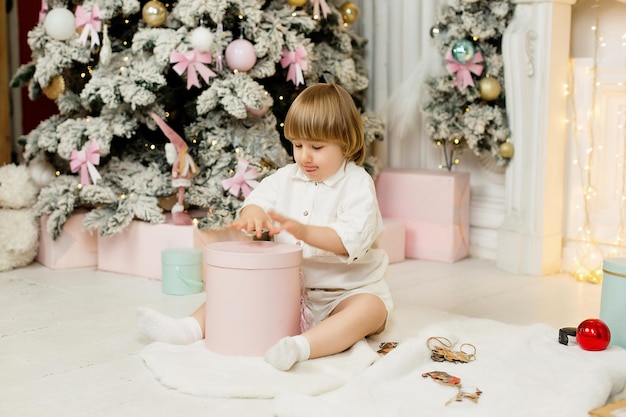 Ritratto di un ragazzo vicino all'albero di Natale che disimballa un regalo per Natale