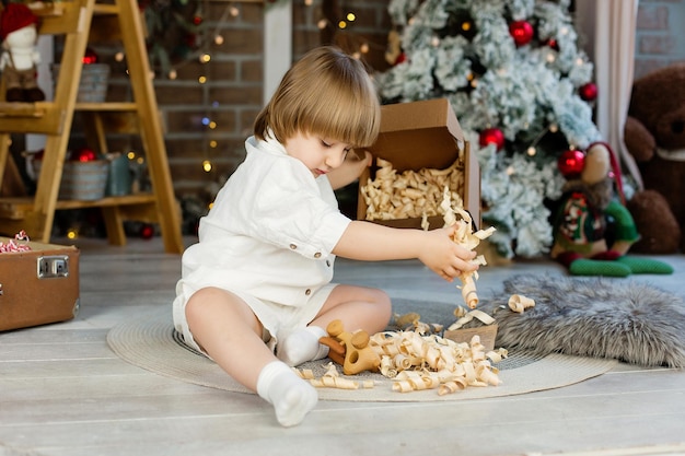 Ritratto di un ragazzo vicino all'albero di Natale che disimballa un regalo per Natale