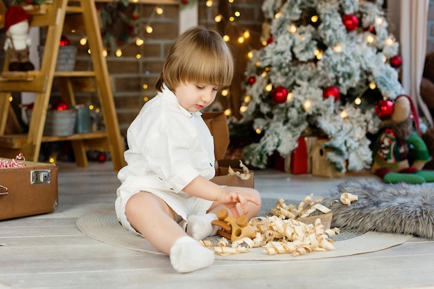 Ritratto di un ragazzo vicino all'albero di Natale che disimballa un regalo per Natale