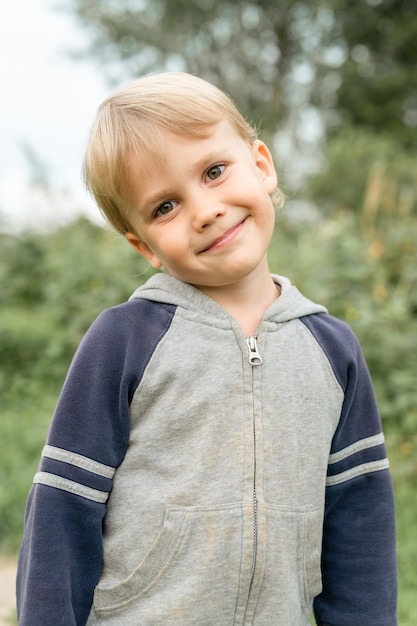 Ritratto di un simpatico bambino di quattro anni sorridente felice e candido ragazzo europeo in natura nel giardino in estate