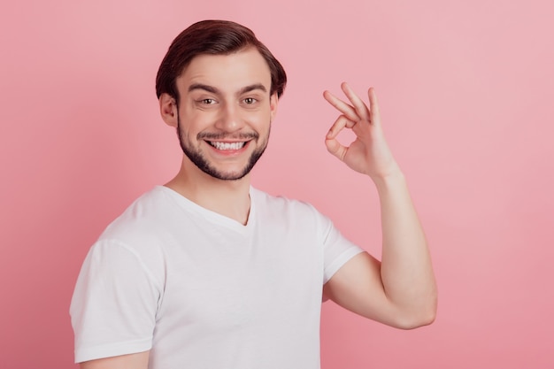 Ritratto di un sognatore che alza la mano mostra un gesto ok sorriso raggiante guarda la telecamera su sfondo rosa