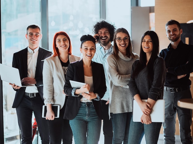 Ritratto di un team di business creativo di successo che guarda l'obbiettivo e sorridente. Diversi uomini d'affari che stanno insieme nello spazio di coworking dell'ufficio di avvio. Messa a fuoco selettiva.