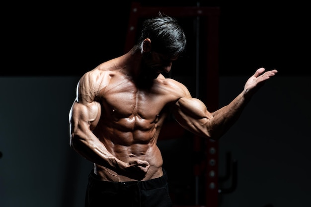 Ritratto di un uomo adulto fisicamente in forma che mostra il suo corpo ben allenato - modello di fitness bodybuilder atletico muscolare in posa dopo gli esercizi