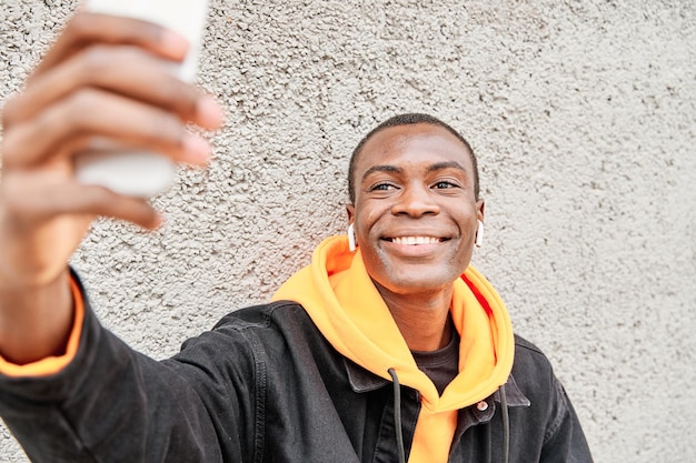 Ritratto di un uomo afroamericano che effettua una videochiamata con il suo smartphone in città