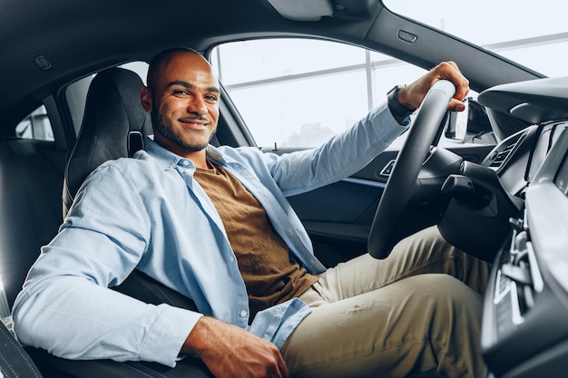 Ritratto di un uomo afroamericano felice bello che si siede nella sua fine appena acquistata dell'automobile