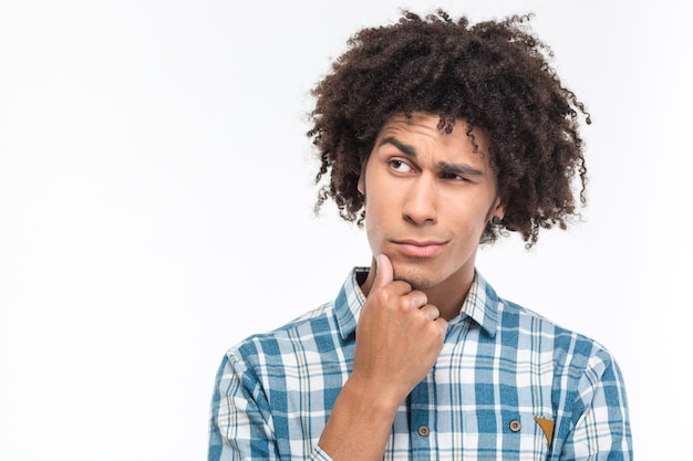 Ritratto di un uomo afroamericano pensieroso con capelli ricci che distoglie lo sguardo isolato su un muro bianco white