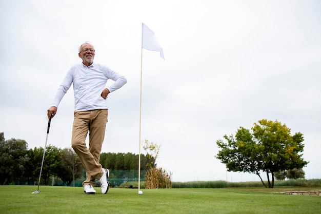 Ritratto di un uomo anziano attivo che gioca a golf sul campo da golf e si gode il tempo libero all'aperto.