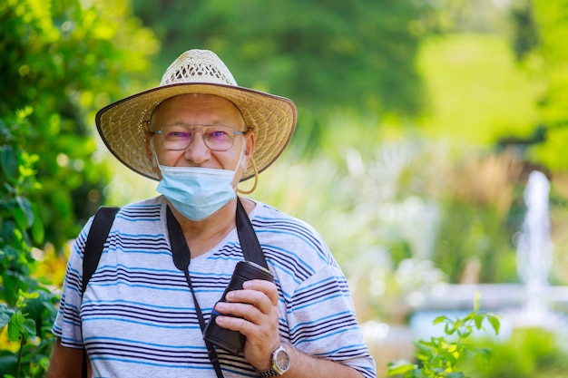 Ritratto di un uomo anziano che indossa una maschera medica durante il coronavirus in un parco