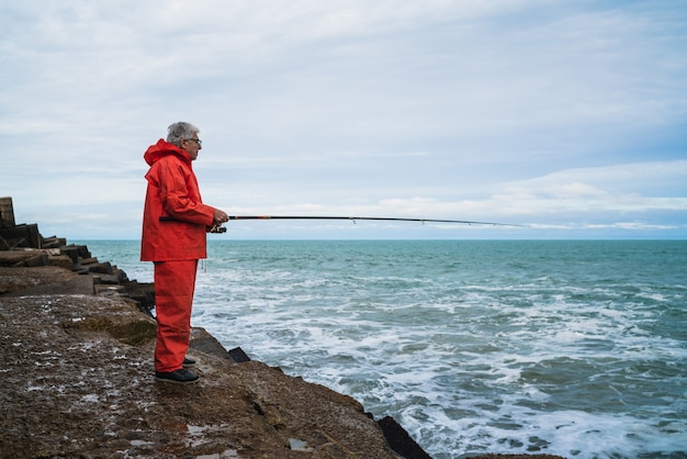 Ritratto di un uomo anziano che pesca in mare. Concetto di pesca.