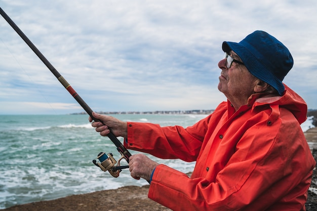 Ritratto di un uomo anziano che pesca in mare, godersi la vita. Concetto di pesca e sport.