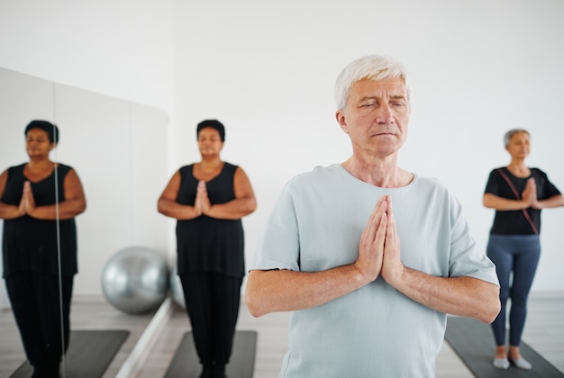 Ritratto di un uomo anziano con gli occhi chiusi che pratica la meditazione durante la lezione di yoga di gruppo