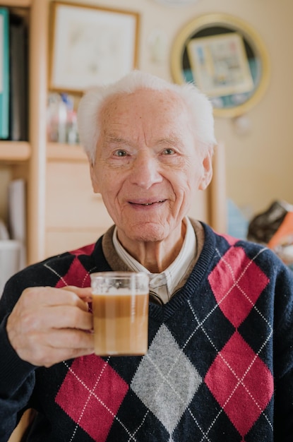 Ritratto di un uomo anziano sorridente che tiene in mano una bevanda