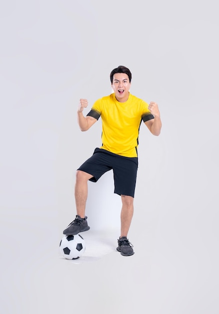 Ritratto di un uomo asiatico che gioca a calcio su sfondo bianco