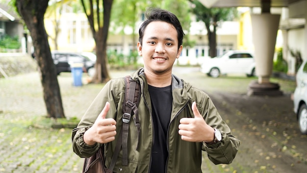 Ritratto di un uomo asiatico sorridente che indossa una borsa con il gesto giusto