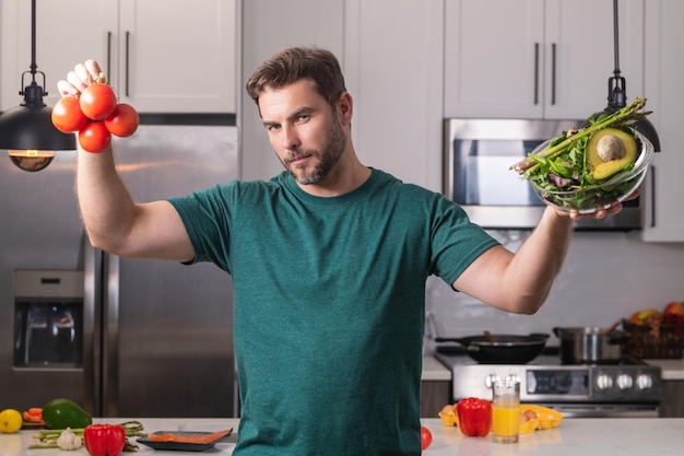 Ritratto di un uomo attraente che prepara un pasto naturale fresco per perdere peso in cucina a casa al chiuso bello