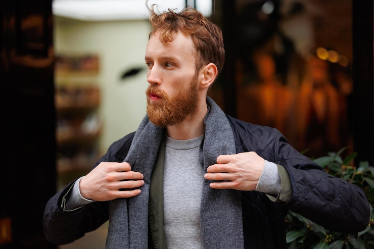 Foto ritratto di un uomo barbuto elegantemente vestito in posa all'aperto