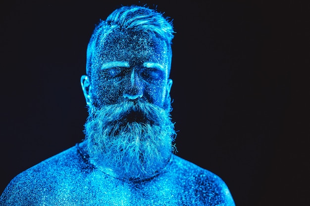Ritratto di un uomo barbuto. L'uomo è dipinto in polvere ultravioletta.