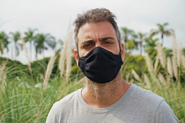 Ritratto di un uomo brasiliano che indossa una maschera protettiva mentre si trova nel parco.