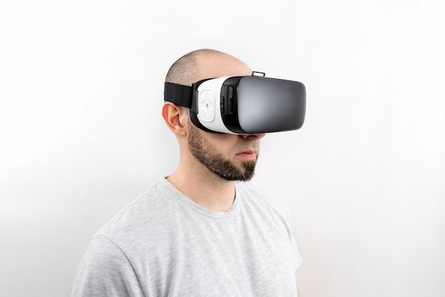 Ritratto di un uomo caucasico con gli occhiali VR su sfondo bianco. Il concetto di realtà virtuale e intrattenimento moderno