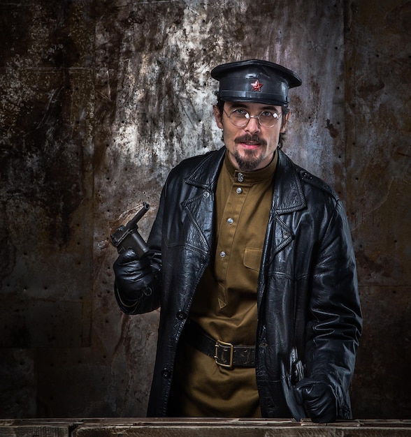 Ritratto di un uomo che indossa un costume con una pistola in piedi contro il muro