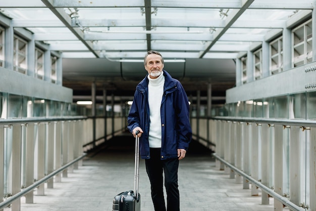 Ritratto di un uomo con i bagagli in piedi sul marciapiede all'aeroporto