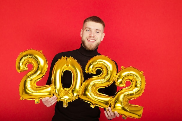 Ritratto di un uomo con i numeri 2022 su sfondo rosso. Il nuovo anno in arrivo