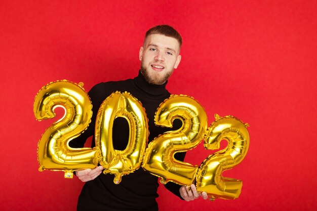 Ritratto di un uomo con i numeri 2022 su sfondo rosso. Il nuovo anno in arrivo