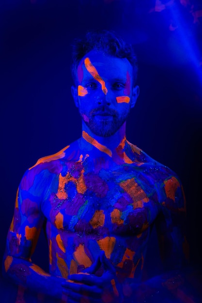 Ritratto di un uomo con trucco ultravioletto e luce al neon in stile cyberpunk