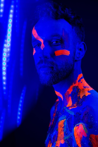 Ritratto di un uomo con trucco ultravioletto e luce al neon in stile cyberpunk