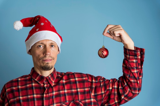 Ritratto di un uomo con un berretto di San Nicola e una camicia rossa a scacchi su sfondo blu