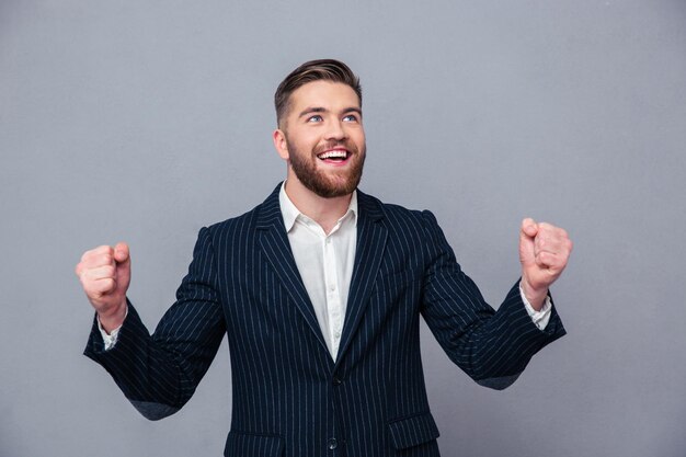 Ritratto di un uomo d'affari allegro che celebra il suo successo sul muro grigio