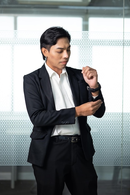 Ritratto di un uomo d'affari asiatico in piedi guarda la fotocamera in un ufficio moderno