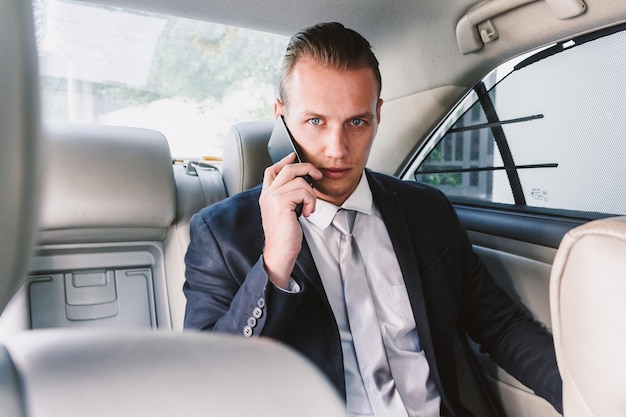 Ritratto di un uomo d'affari che risponde allo smartphone mentre è seduto in macchina