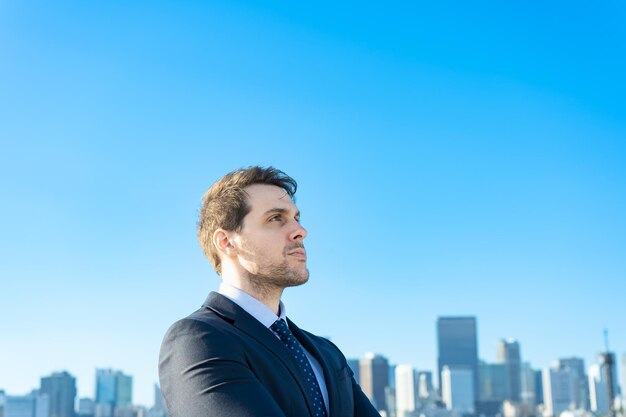 Ritratto di un uomo d'affari, cielo blu e edifici di una grande città