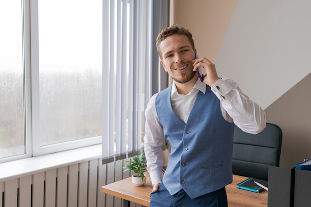 Ritratto di un uomo d'affari di successo con la barba che parla al telefono sorridendo felicemente